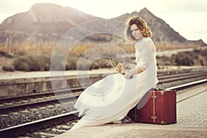 Pensive bride with a red suitcase