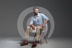 Pensive brunette man in blue shirt sitting on the chair