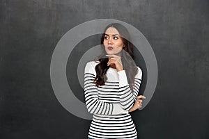 Pensive brunette woman in sweater holding her chin