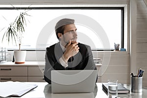 Pensive businessman distracted from computer work thinking in office