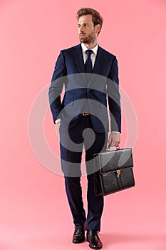 Pensive businessman holding a briefcase and looking away