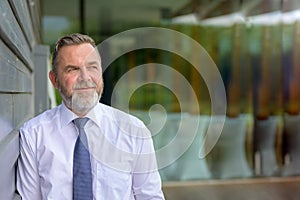 Pensive businessman leaning against a wall thinking deeply