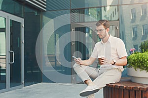 Pensive businessman with phone relaxing outdoors