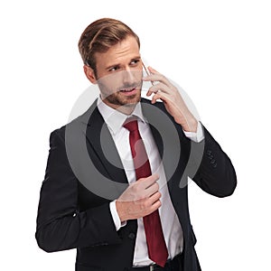 Pensive businessman talking on the phone and looking to side