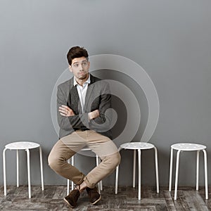 pensive businessman waiting for job interview on chair against