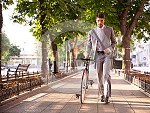 Pensive businessman walking with bicycle