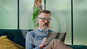 Pensive businessman watching tablet in office hall closeup. Man working computer