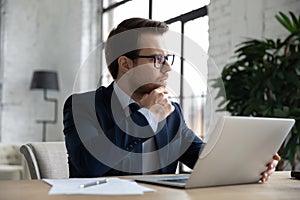 Pensive businessman work on laptop in office thinking