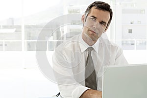 Pensive businessman working on laptop in office