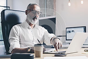 Pensive businessman working at modern coworking office. Confident man using contemporary mobile laptop.