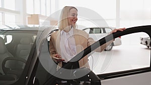 Pensive businesswoman buyer in formal wear choosing new car in showroom.