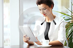 Pensive businesswoman reading an article on tablet computer