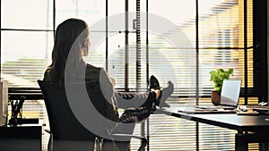 Pensive businesswoman sitting at her workplace and looking out of window thinking about investment strategy or project
