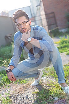 Pensive casual man sits crouched