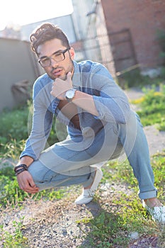 Pensive casual man sits crouched photo