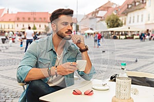 Pensive casual man taking a coffee break while sitting