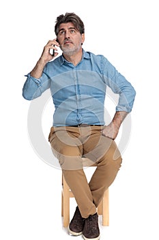 Pensive casual man talking on his phone and looking away