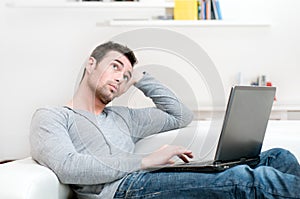 Pensive casual man working on laptop