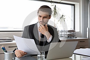 Pensive Caucasian businessman analyze documents in office e