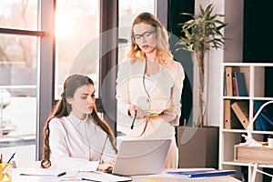 Pensive caucasian businesswomen in formalwear talking while working at modern office