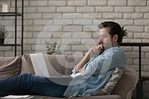 Pensive Caucasian man work on laptop at home thinking