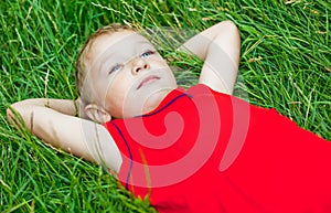 Pensive child day dreaming in fresh grass