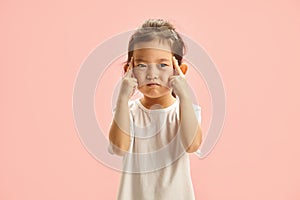 Pensive Child with Fingers on Temple trying remember something stands on pink isolated