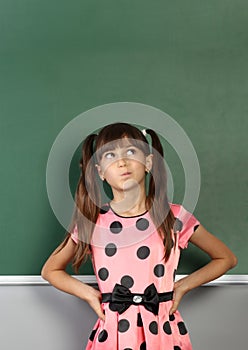 Pensive child girl near blank school blackboard