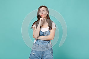 Pensive confused young brunette woman girl in casual denim clothes posing isolated on blue turquoise background. People