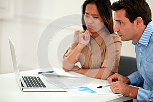 Pensive coworkers team looking at laptop