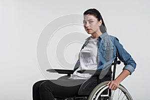 Pensive crippled woman touching wheelchair
