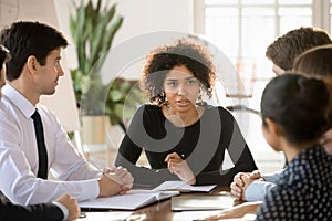 Pensive diverse employees discuss ideas at meeting together