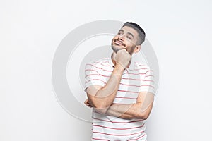 Pensive dreaming positive man in t-shirt standing looking away, thinking about something pleasant.