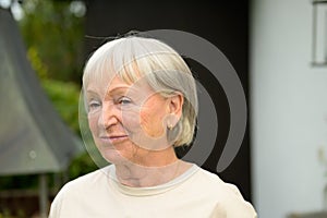 Pensive elderly lady pursing her lips with a thoughtful smile