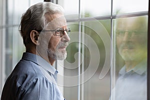 Pensive elderly mature senior man in eyeglasses looking in distance.