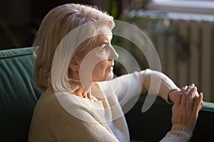 Pensive elderly woman look in distance thinking or mourning