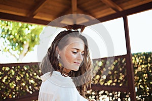 Pensive elegant woman in white shirt in patio