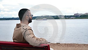 Pensive fashion man relaxing sitting bench contemplate ship floating river city panorama landscape