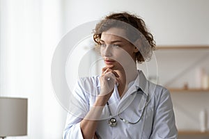 Pensive female doctor look in distance thinking