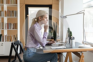 Pensive female entrepreneur looking at window and thinking