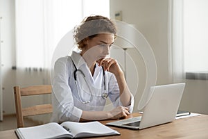 Pensive female GP work on laptop thinking