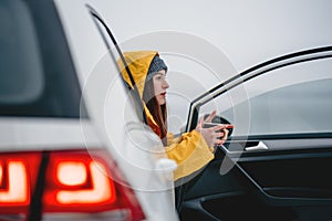 Pensive female sitting in car and get warm with cup of tea