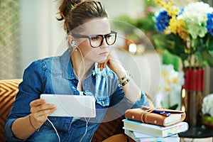 Pensive female with white headphones and tablet PC study online