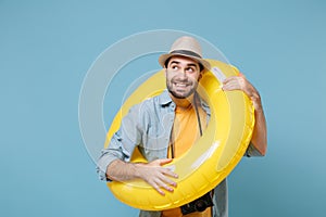 Pensive funny traveler tourist man in yellow clothes with photo camera isolated on blue background. Passenger traveling