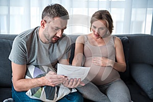 Pensive future parents looking at ultrasound picture of baby