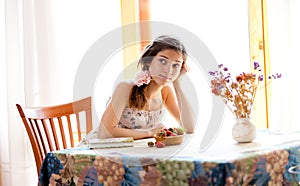 Pensive girl with book sitting at table indoor