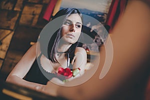 Pensive girl with drink at cafe with her friend