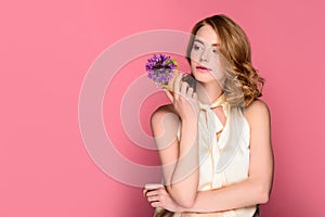 pensive girl holding waffle cone with violet flower and looking away