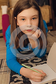 Pensive girl lying on floor and drawing pencil