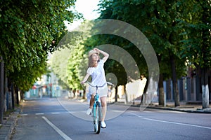 Pensive girl rides on road at retro bike looking up